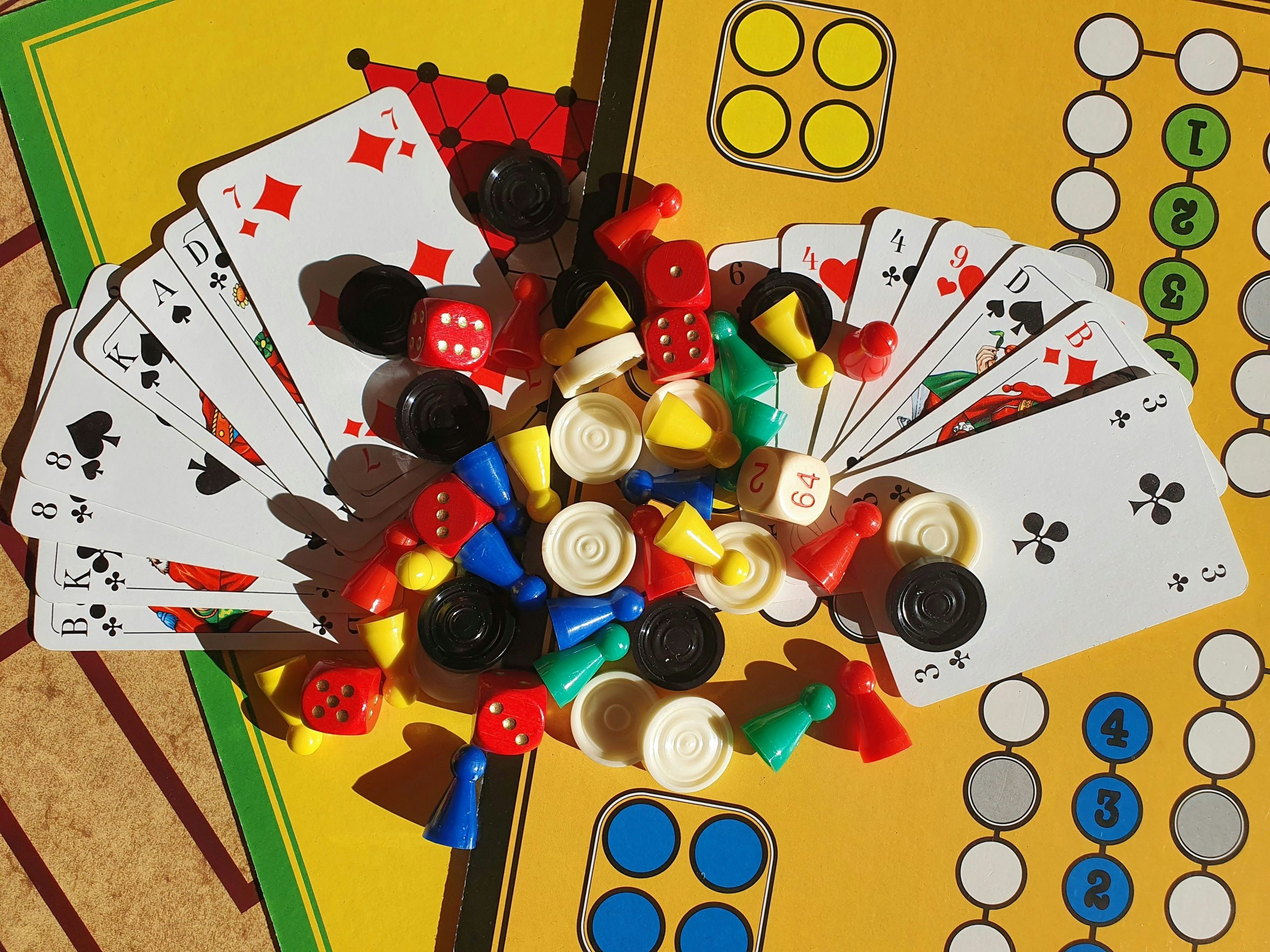 Spelkort och spelpjäser på ett gult Fia-liknande brädspel
